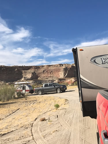 Trucks and Campers on Sand with Desert Mountains in Background