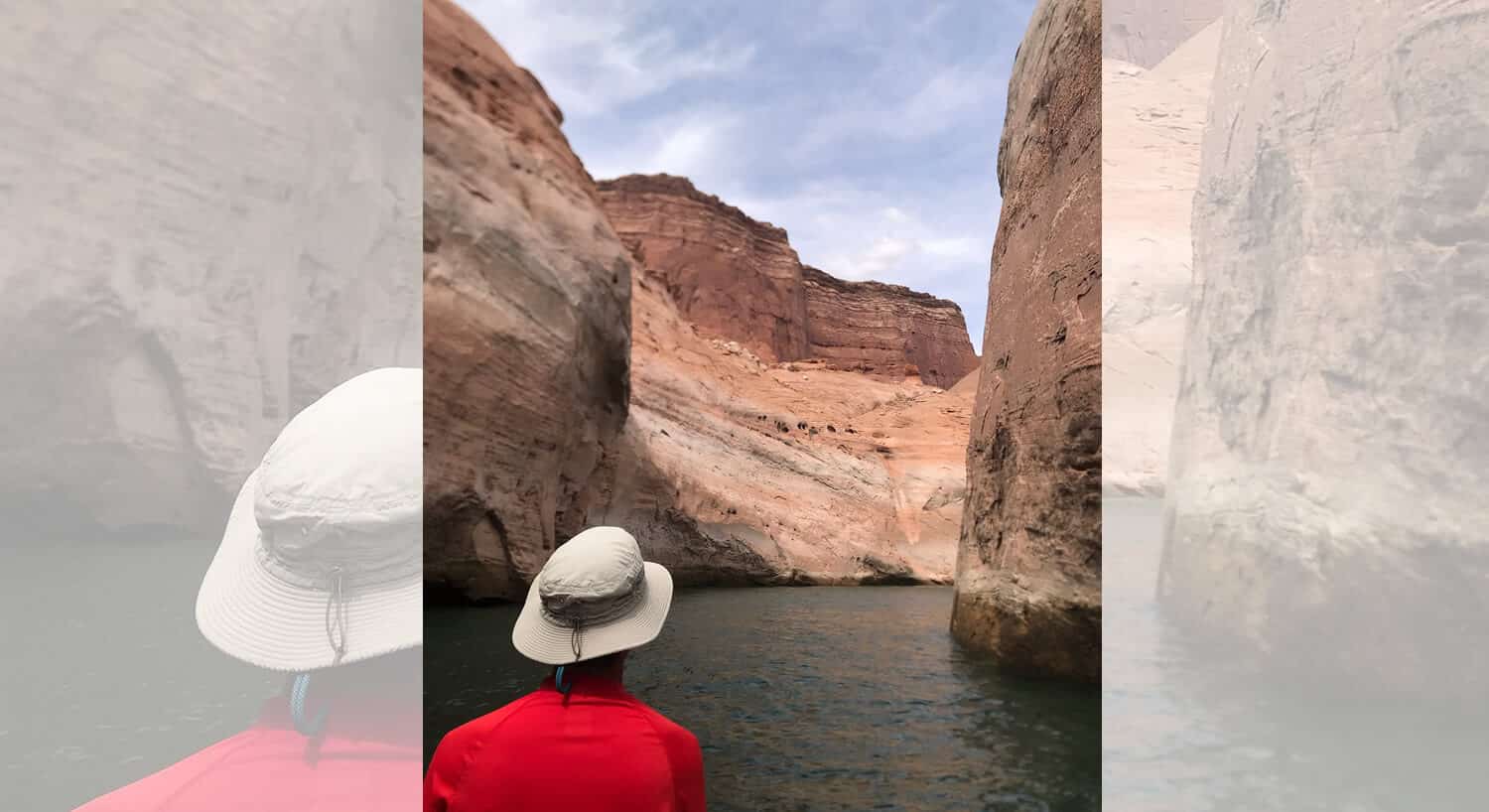 Young man with red sunshirt and tan hat looking down canyon with water running in between tall rock formations
