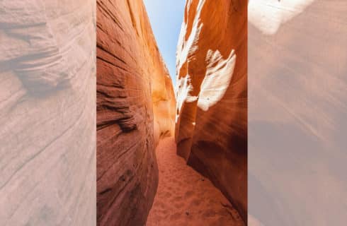 narrow canyon with sandy path with tall rock formations on both sides with sun glistening on rocks